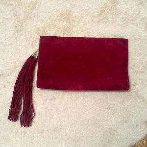 Oversized burgundy faux suede clutch with detachable gold tone chain & tassels.